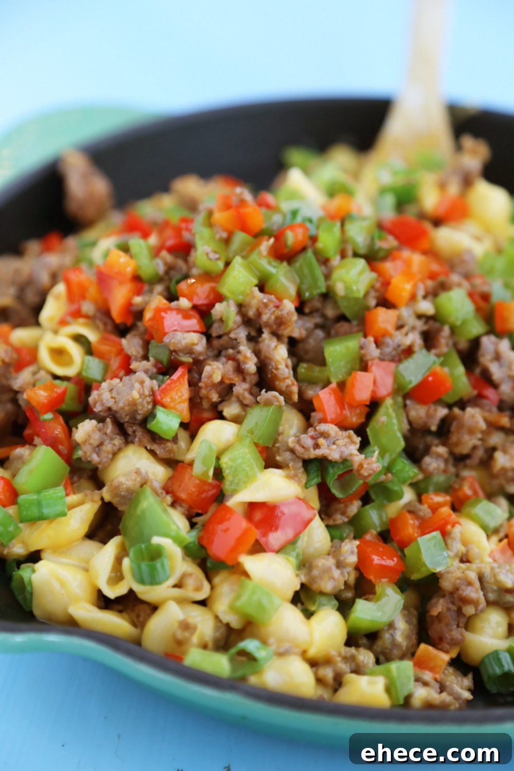 Serving of Spicy Sausage and Bell Pepper Mac and Cheese in a bowl, garnished with fresh green onions.