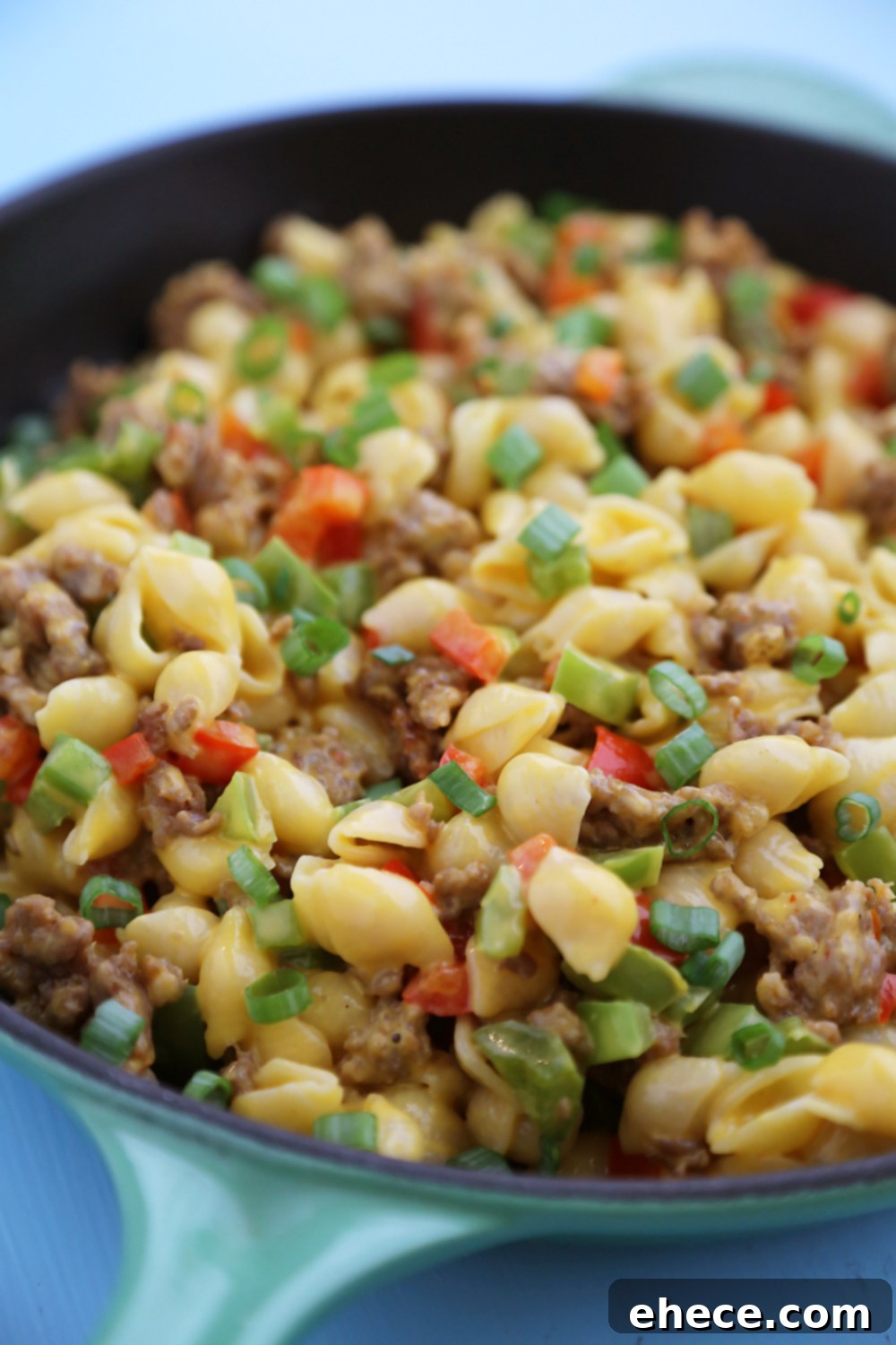 Scoop of Spicy Sausage and Bell Pepper Mac and Cheese being served from a skillet.