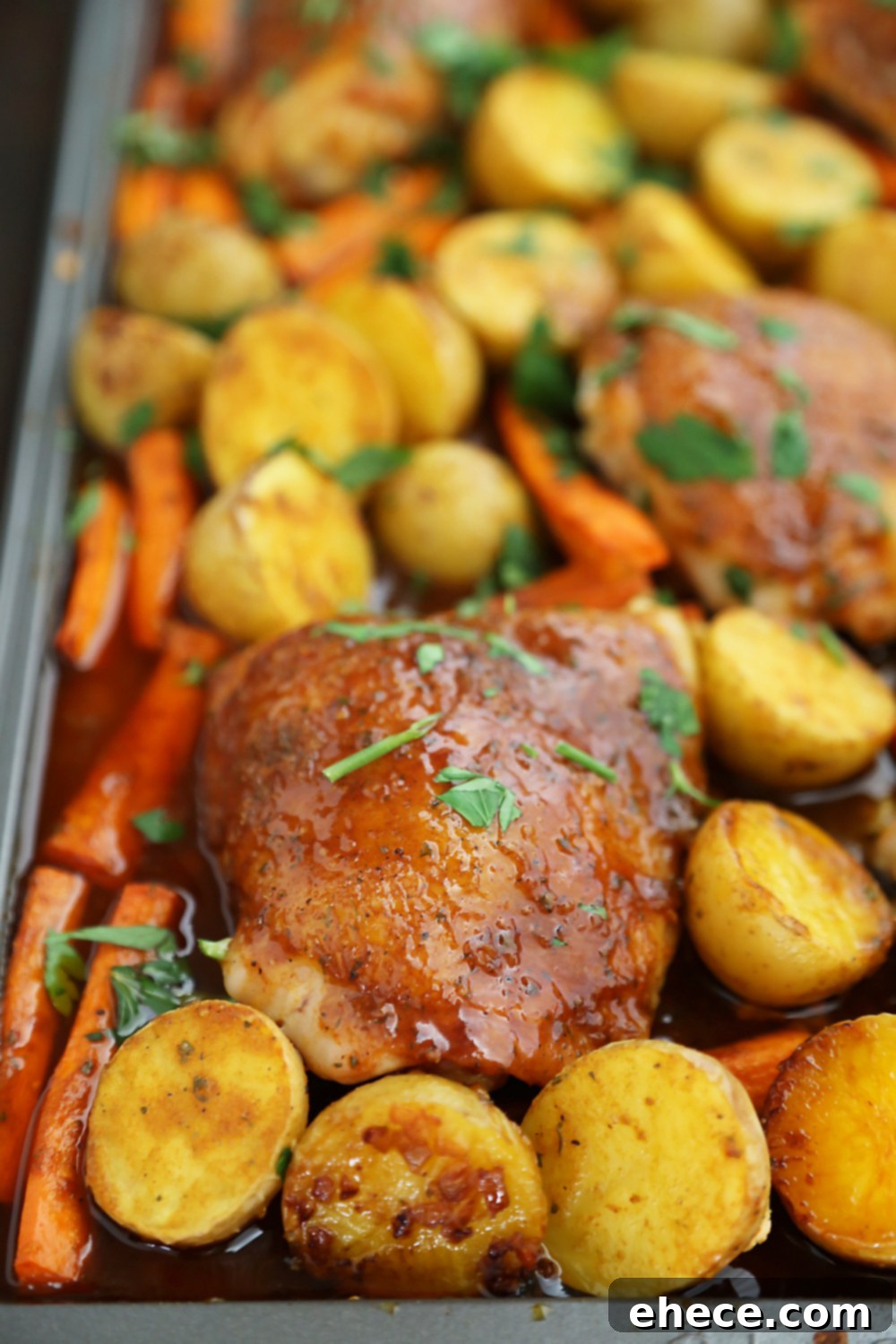Sheet Pan Garlic Ranch Chicken and Roasted Vegetables 6 A close-up of a serving of roasted chicken thigh, potatoes, and carrots with fresh parsley