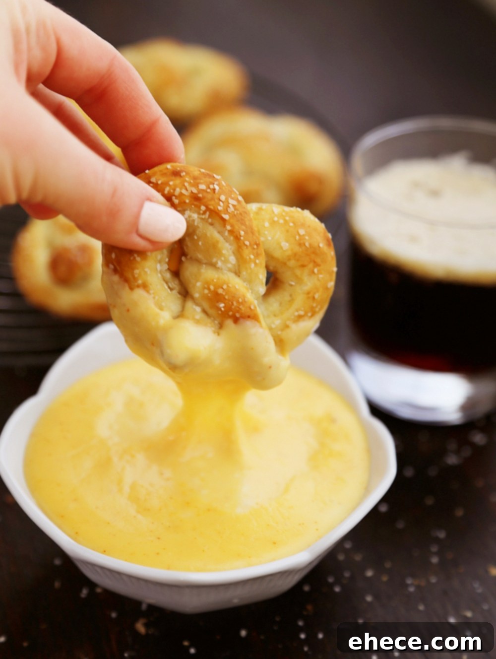 An appetizing shot of several soft pretzels, some dipped in cheese sauce, others with mustard.