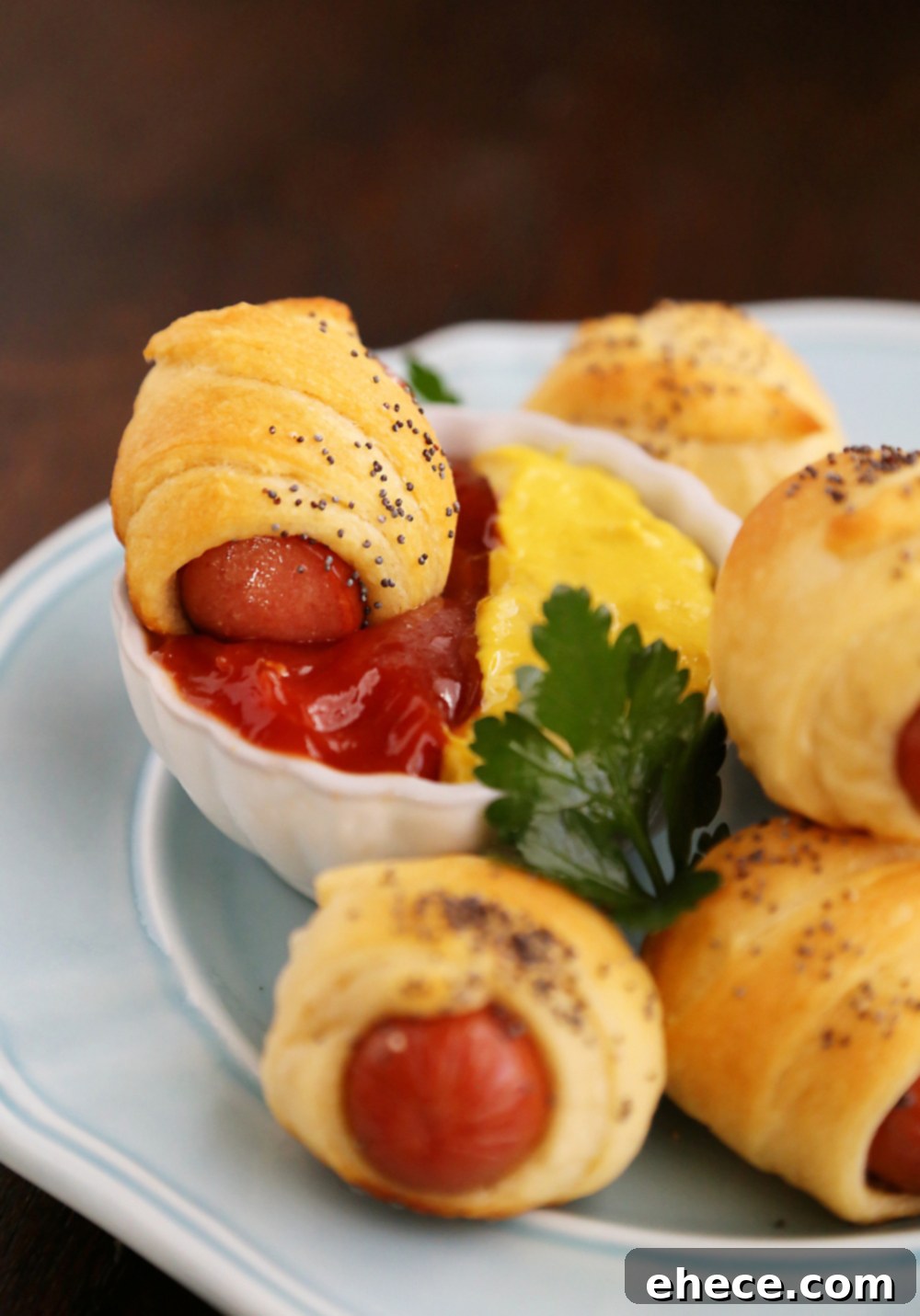 Hands preparing 3-Ingredient Crescent Hot Dog Rollups with poppy seeds before baking. Easy and fun recipe.