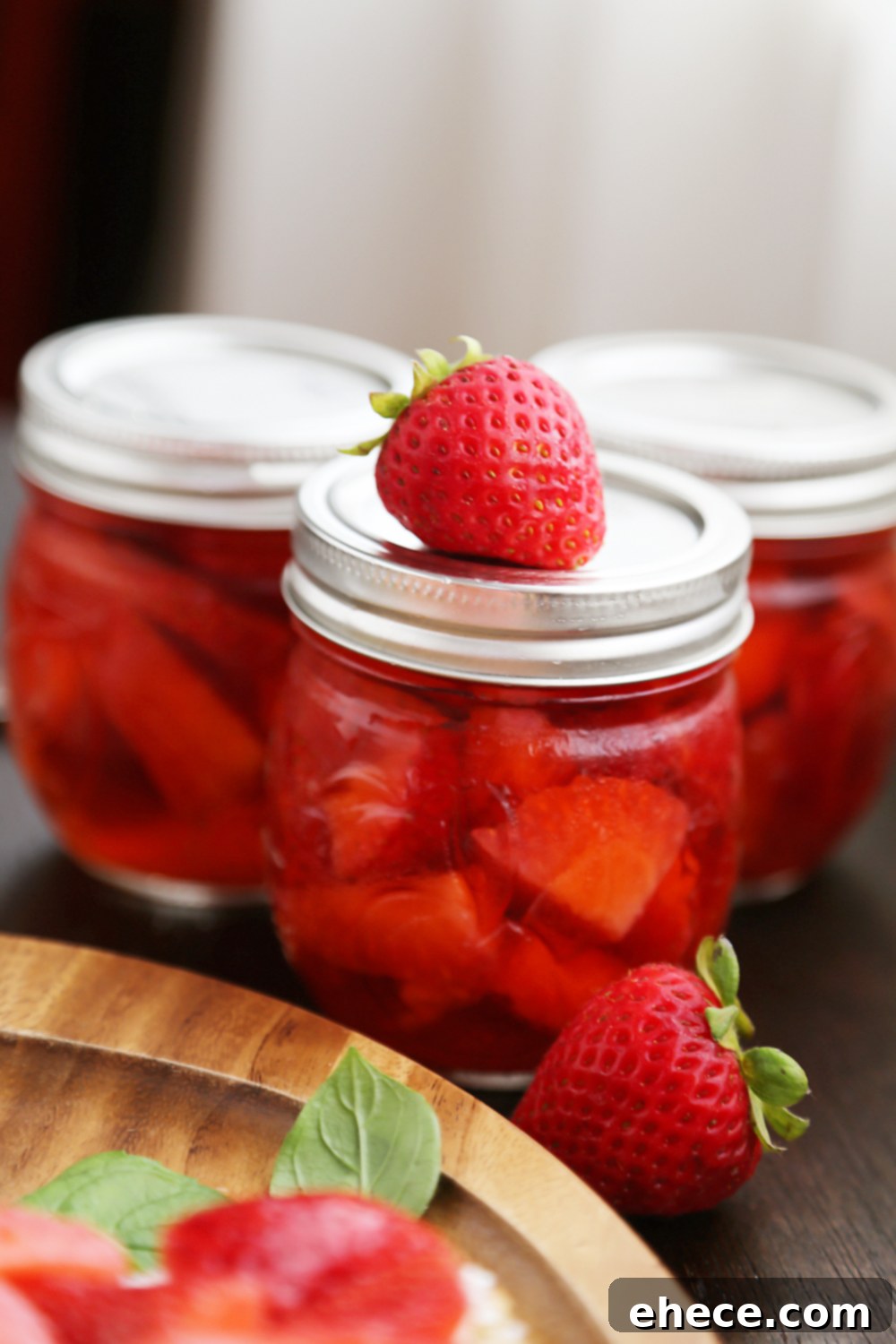 Hand holding Vanilla Bean Pickled Strawberries with Goat Cheese Crostini - A delightful summer appetizer ready to be enjoyed. Thecomfortofcooking.com