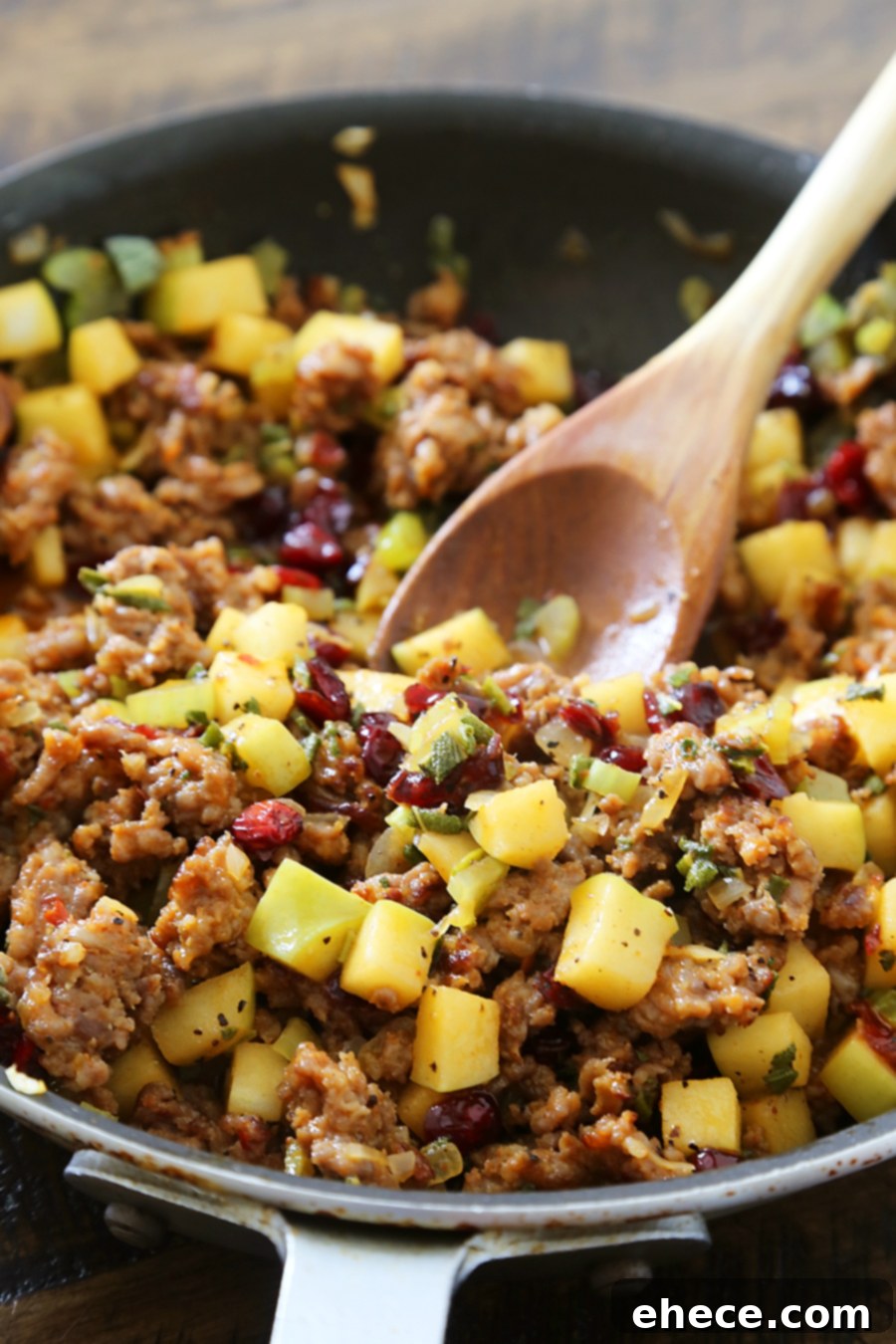 Close-up of golden brown Sausage, Apple, and Cranberry Cornbread Stuffing with fresh sage.