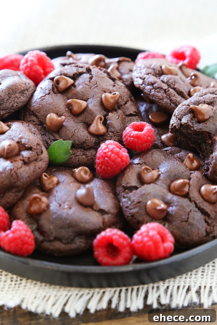 Stack of warm double chocolate cookies showing their soft interior and abundance of chocolate chips, ready to be enjoyed.