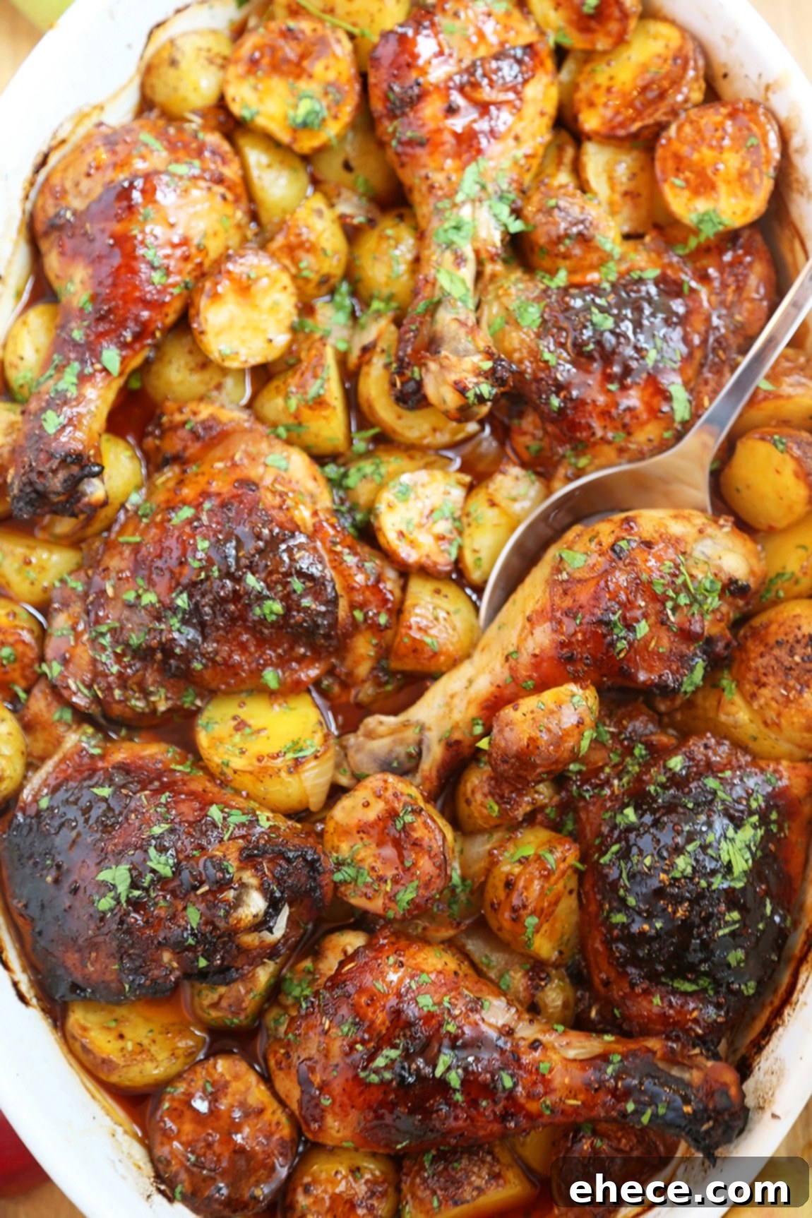 Three roasted apple cider chicken pieces with potatoes and onions on a rustic wooden board, garnished with fresh thyme.