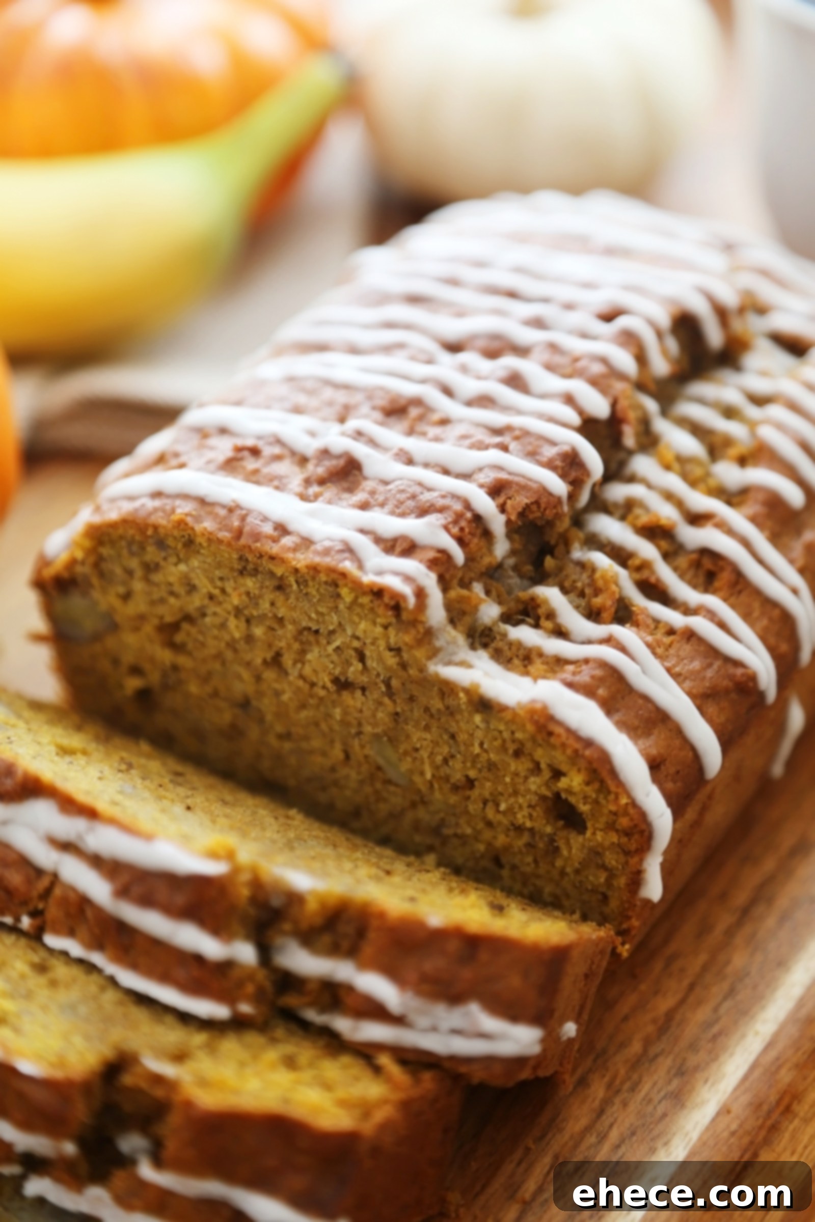 Autumn Pumpkin Banana Bread with Vanilla Drizzle 7 Hand holding a slice of Pumpkin Banana Bread, showing its fluffy texture and vanilla glaze, with a full loaf in the background.