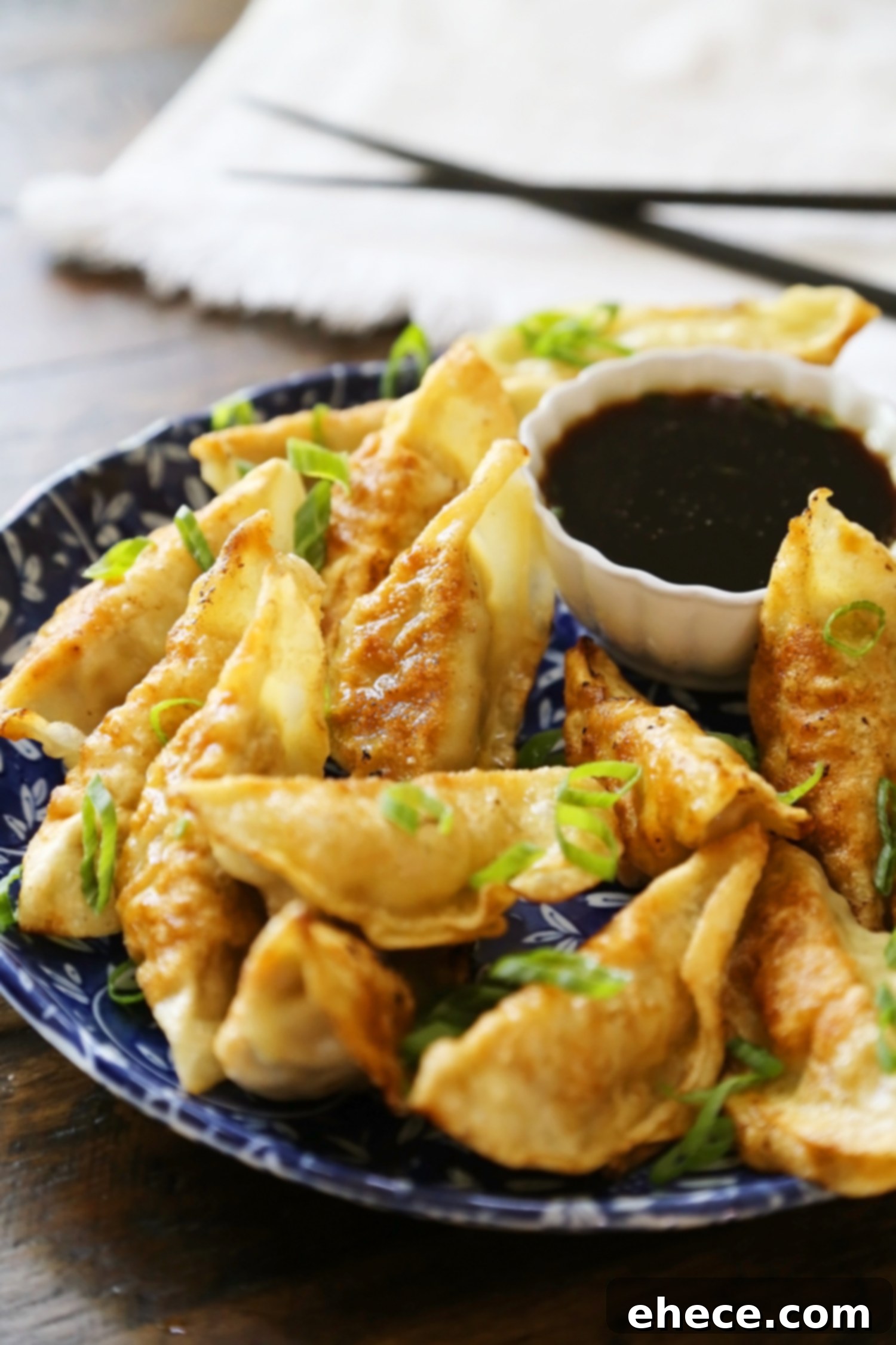Simple Asian Dumplings with Zesty Soy Ginger Dip 2 Easy Asian Dumplings with Soy-Ginger Dipping Sauce - Crispy, tender steamed potstickers, made easily in one skillet! A close-up shot of golden-brown potstickers arranged on a plate, ready to be dipped.