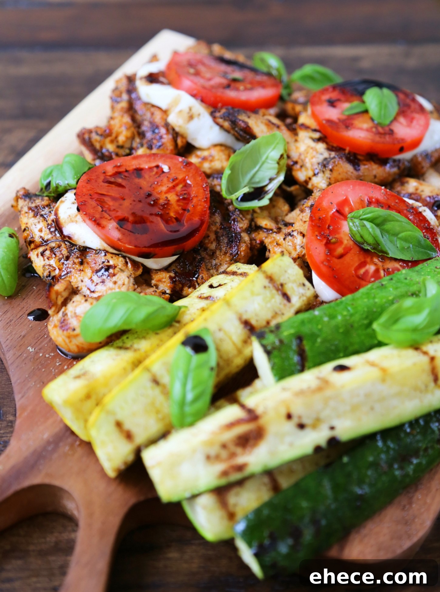 Vibrant Caprese Chicken with Grilled Summer Squash 3 Closeup of grilled chicken topped with melting mozzarella and a slice of tomato