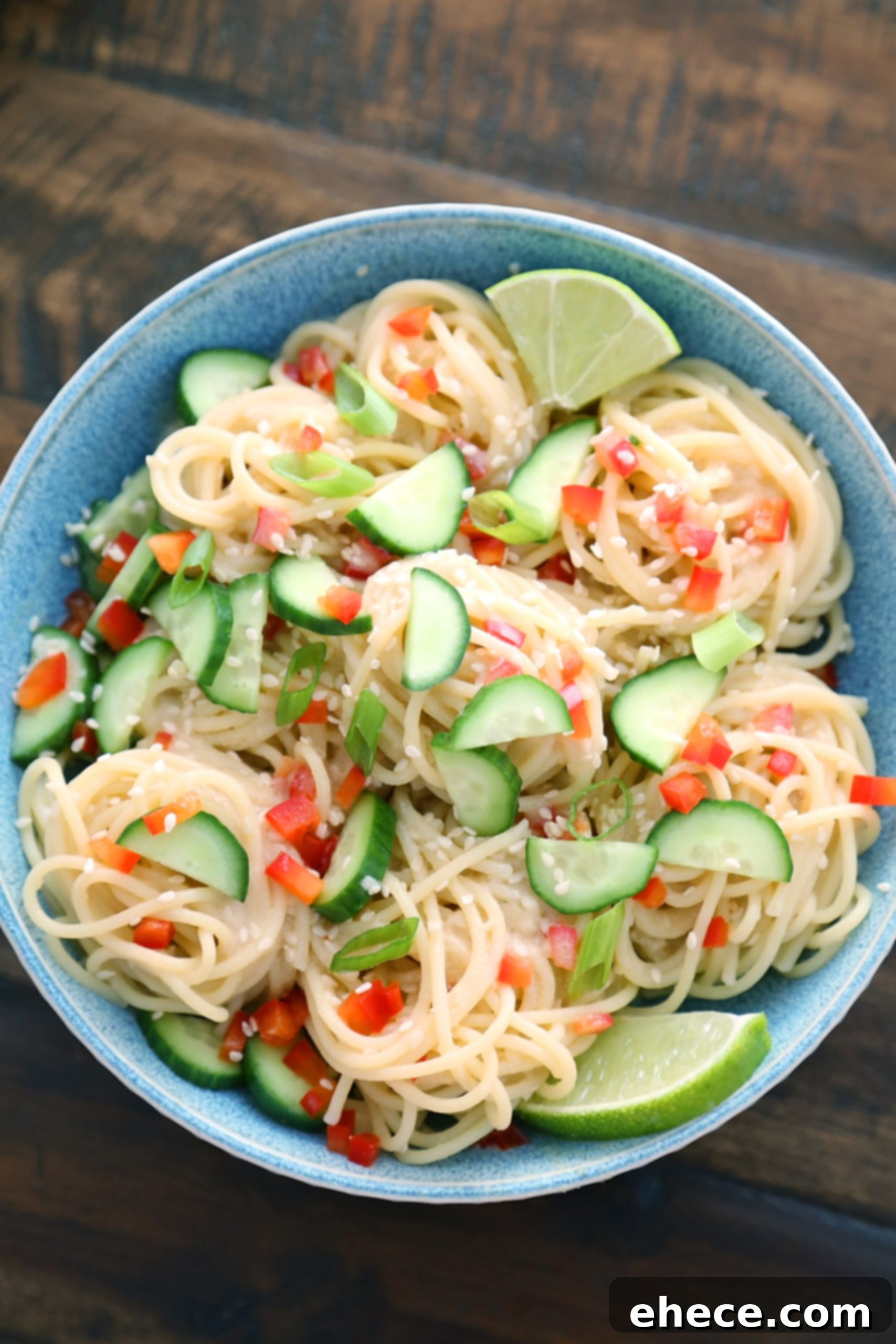 Close-up of fresh ingredients being prepared for the cold noodle salad, including sliced cucumbers and green onions.