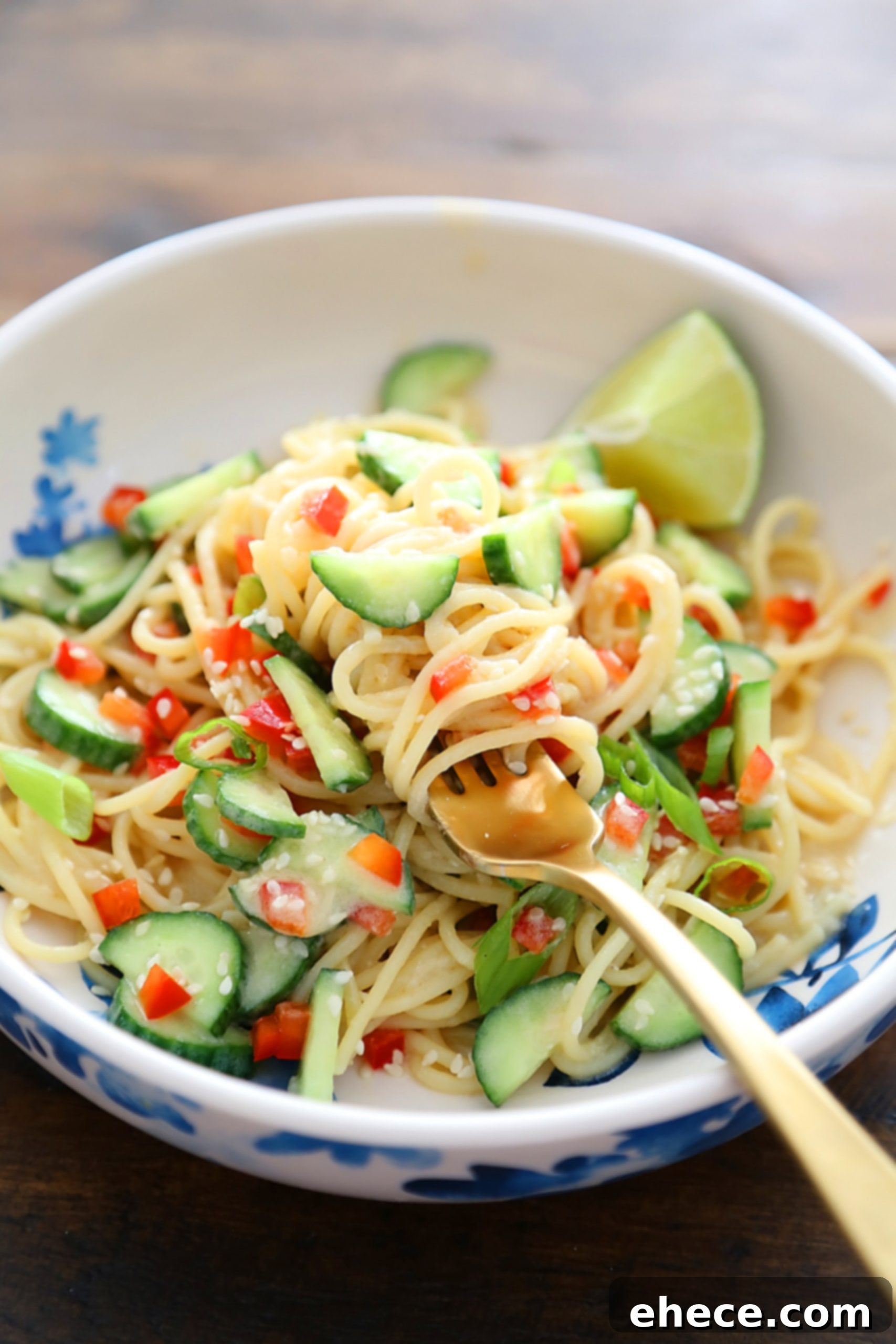 Individual serving bowls filled with Cold Sesame Cucumber Noodle Salad, garnished with sesame seeds and fresh lime slices.