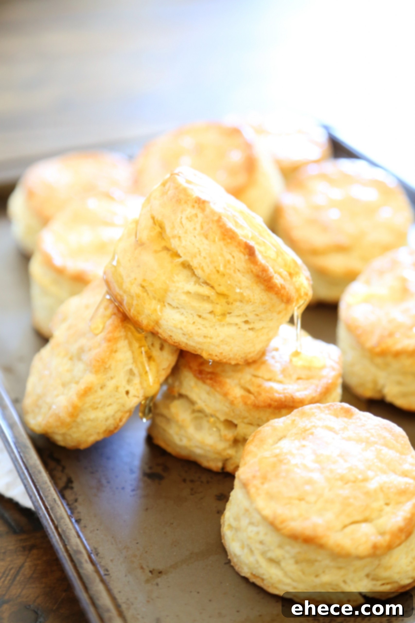 Two hands tearing open a warm buttermilk biscuit to show the fluffy interior