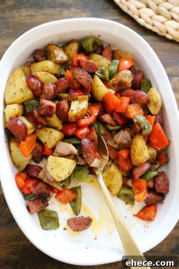 Close-up of colorful roasted vegetables and sausage with herbs and spices.