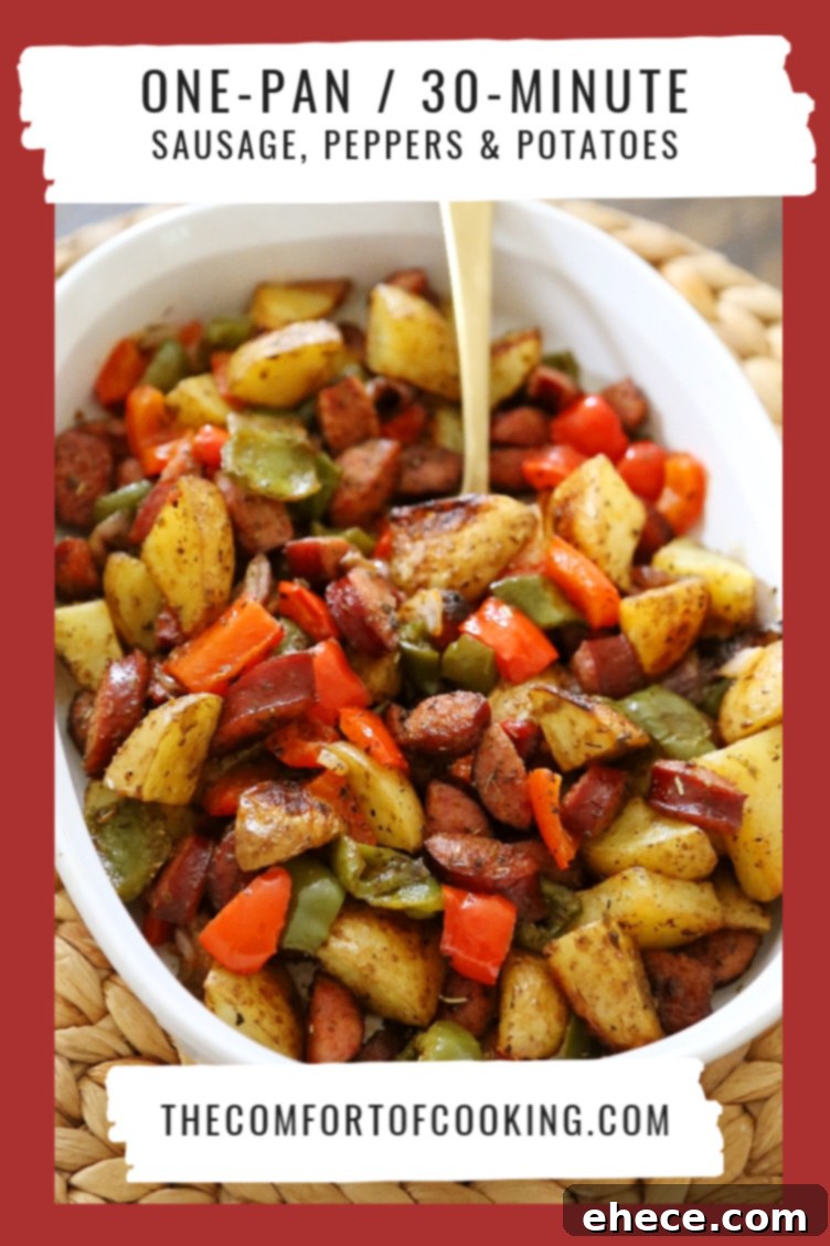 Spread of roasted sausage, peppers, and potatoes on a baking sheet, ready for serving.