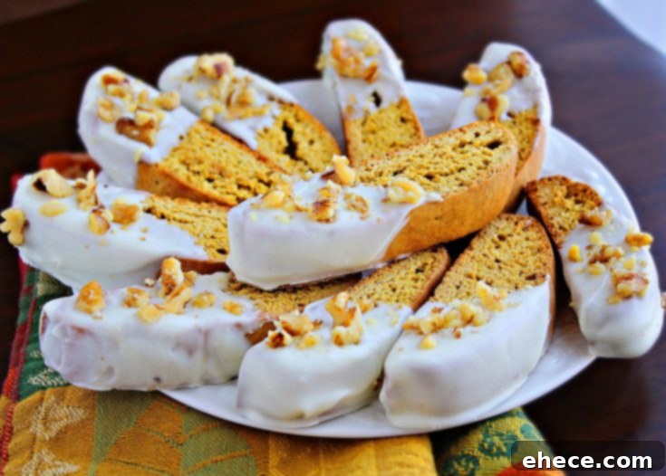 Close-up of a stack of Pumpkin Gingerbread Biscotti, showcasing the white chocolate and walnut topping.