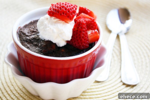A delectable close-up of Easy Chocolate Bread Pudding topped with a generous dollop of vanilla whipped cream and fresh strawberries, served in a ramekin.