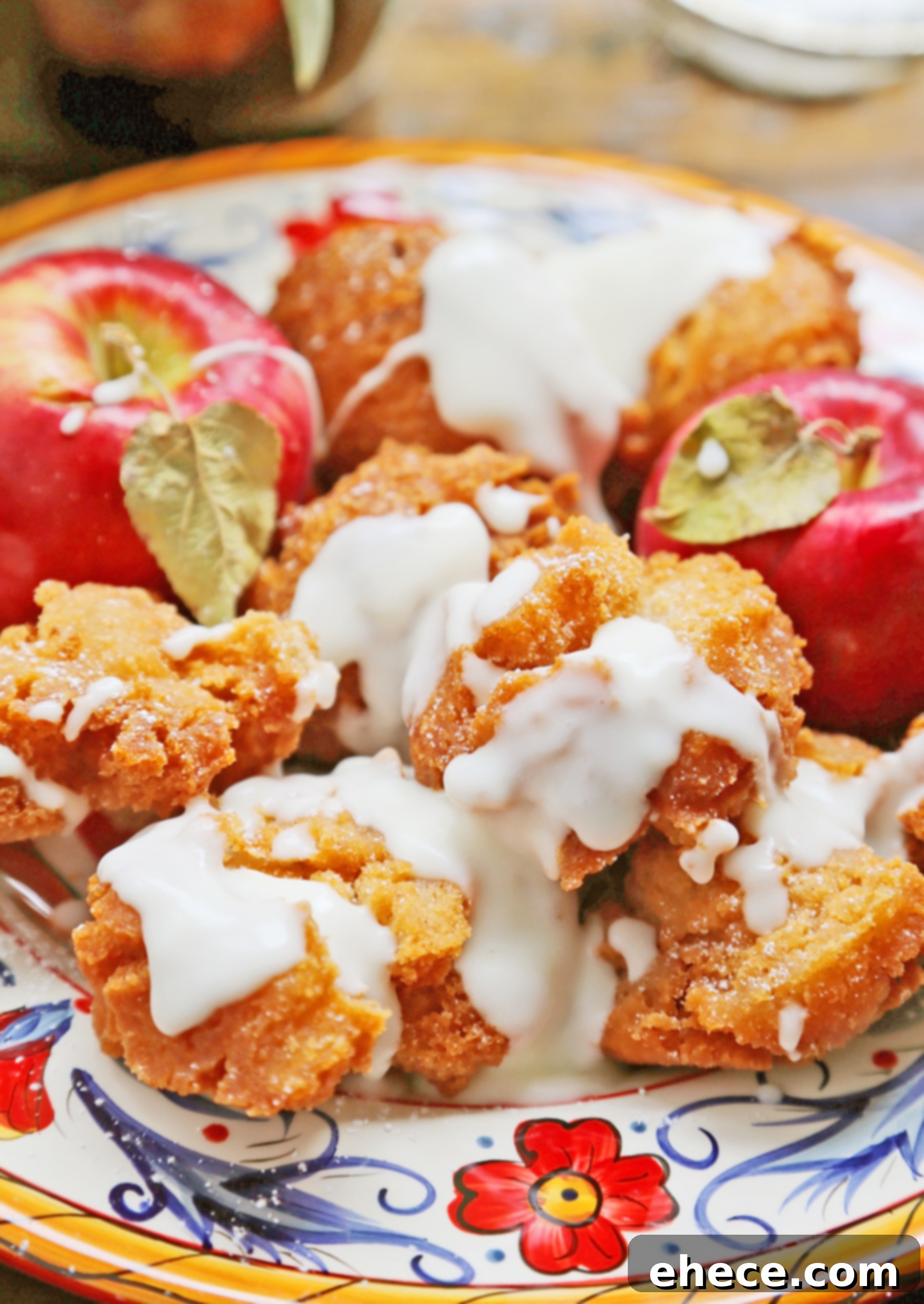 Pile of golden brown apple fritters, some drizzled with glaze