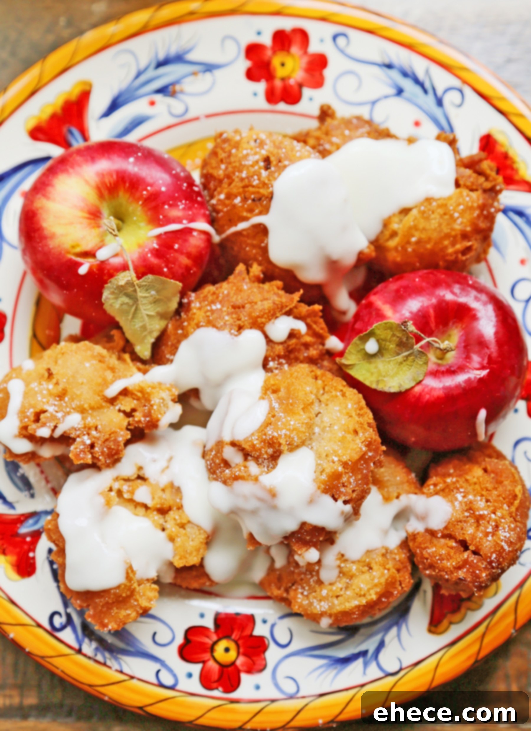 Several glazed apple fritters on a white plate with a fork