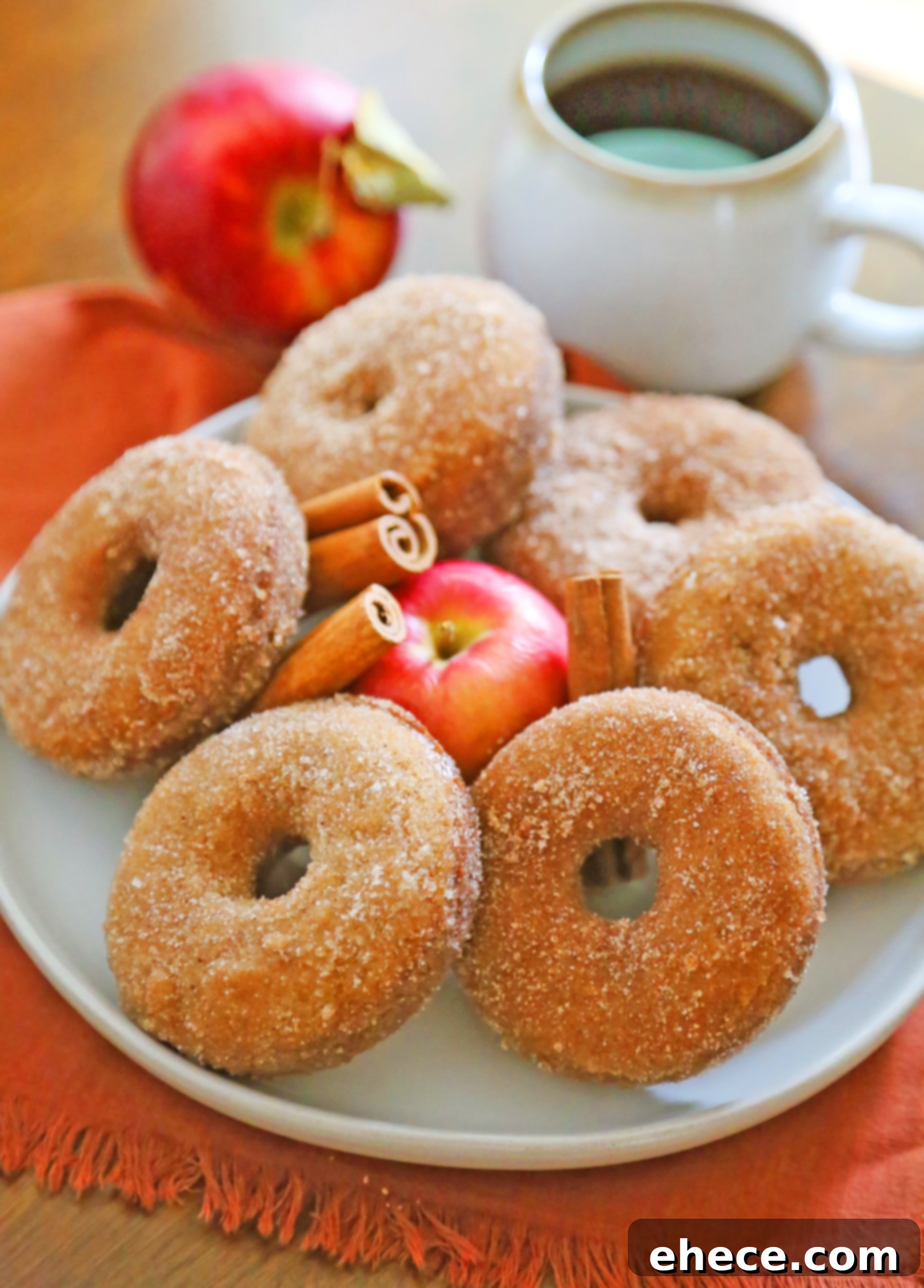 A stack of perfectly coated baked apple cider donuts on a wooden board, ready to be served.