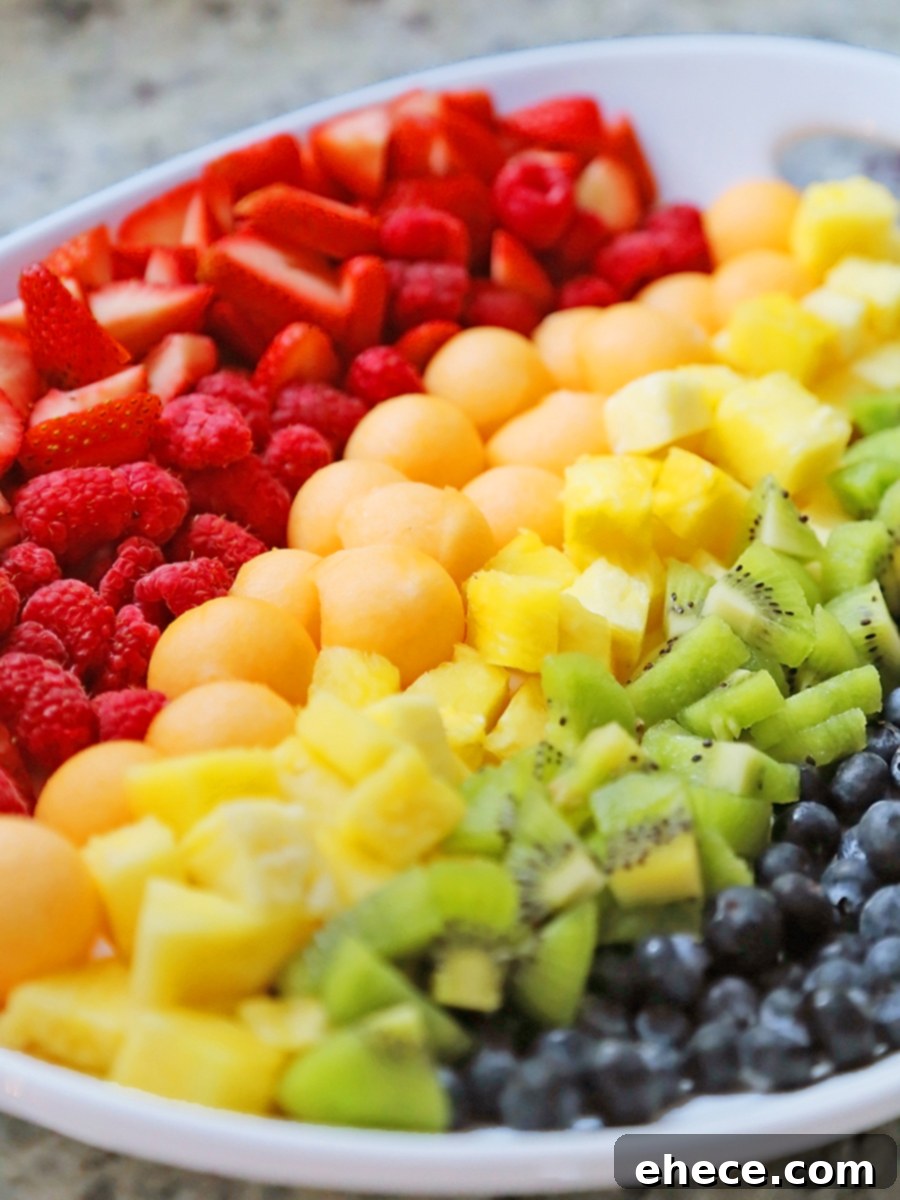 Close-up of fresh strawberries, raspberries, and cantaloupe in a fruit salad, showcasing their vibrant colors and textures.