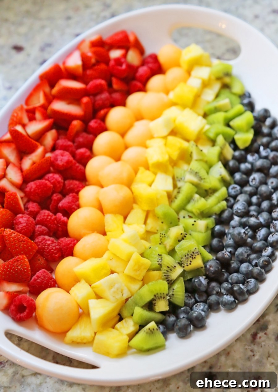 An assembled rainbow fruit salad on a decorative platter, ready for serving.