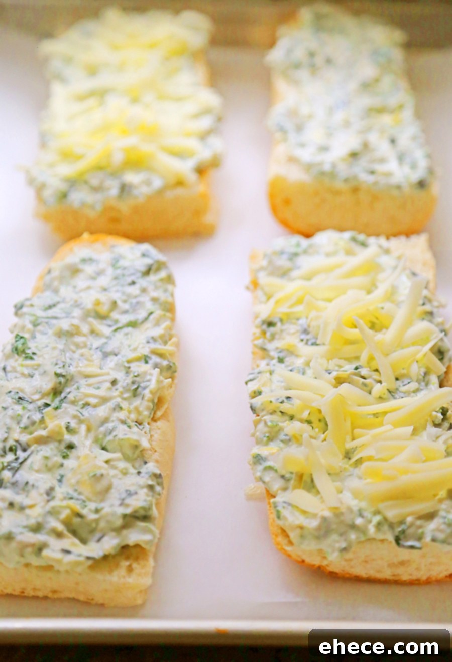 Two halves of Cheesy Spinach Artichoke Bread, freshly baked, on a baking sheet.