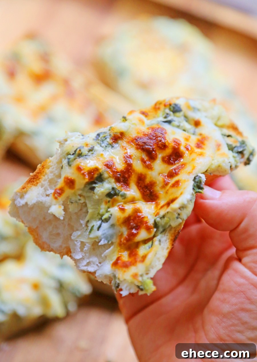 Close-up of a slice of cheesy spinach artichoke bread being pulled from the loaf, showing the melted cheese and creamy filling.