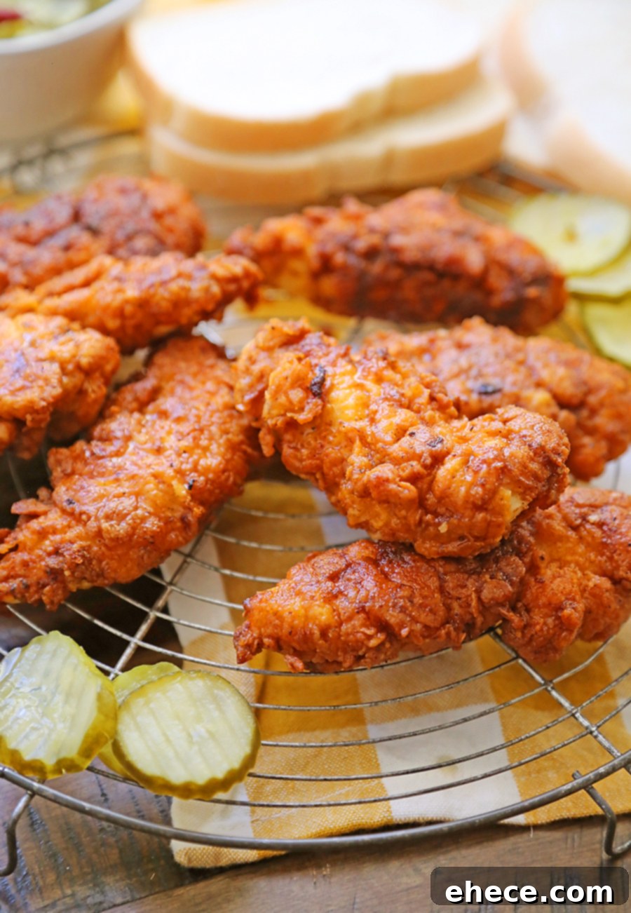 Crispy golden-brown Nashville Hot Chicken Tenders on a plate, garnished with pickles.