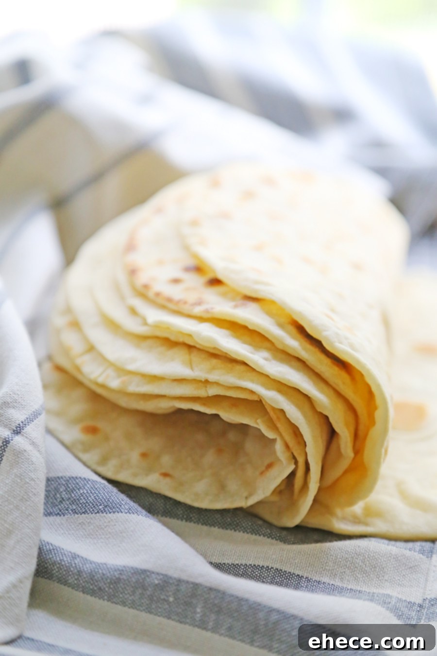 Pillowy Soft Homemade Flour Tortillas 5 A young girl, Lillian Rose, happily helping roll out tortilla dough on a floured countertop in the kitchen.