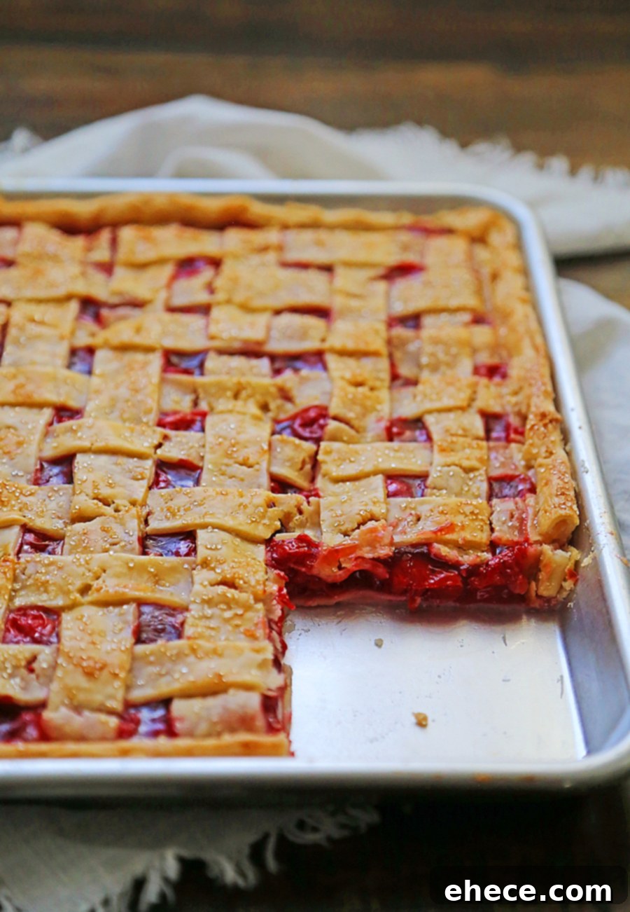 Top-down view of a cooling cherry slab pie, showcasing its golden-brown lattice top and caramelized filling.