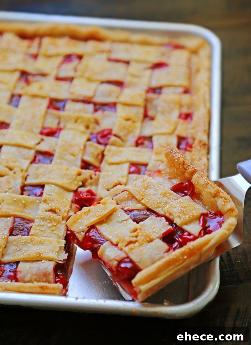 A slice of cherry slab pie being served with a generous scoop of vanilla ice cream, ready to be enjoyed.