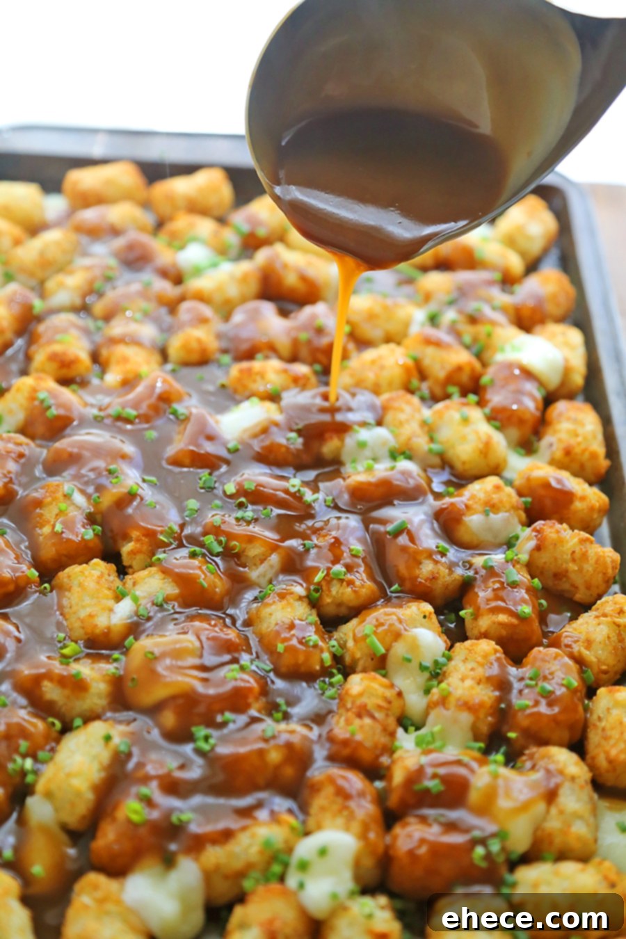 Golden brown crispy Tater Tot Poutine with melted cheese curds and thick gravy