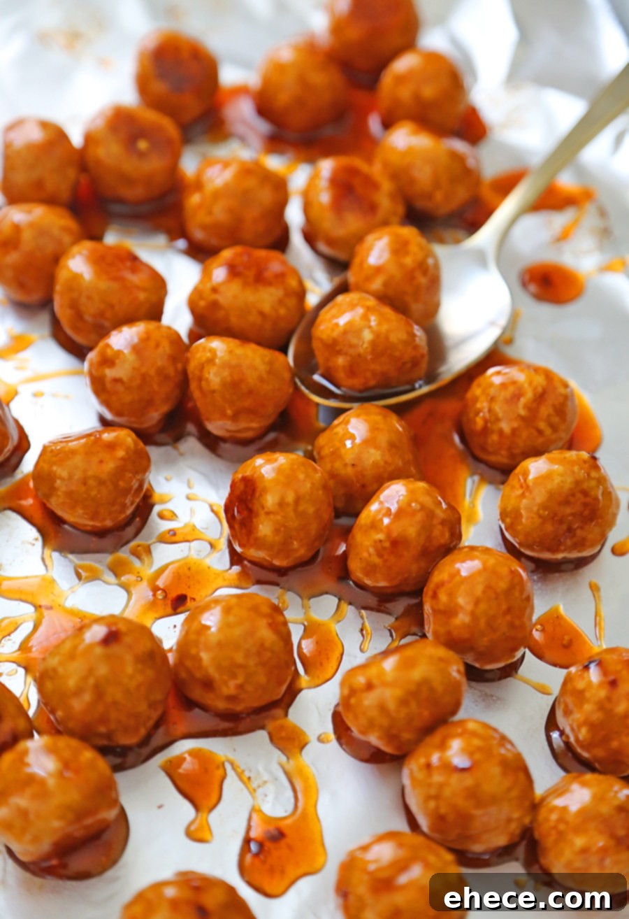 Dynamite Chicken Meatballs 4 Firecracker Chicken Meatballs coated in sauce, garnished with green onions