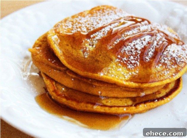 Stacked pumpkin spice pancakes with syrup and a warm glow