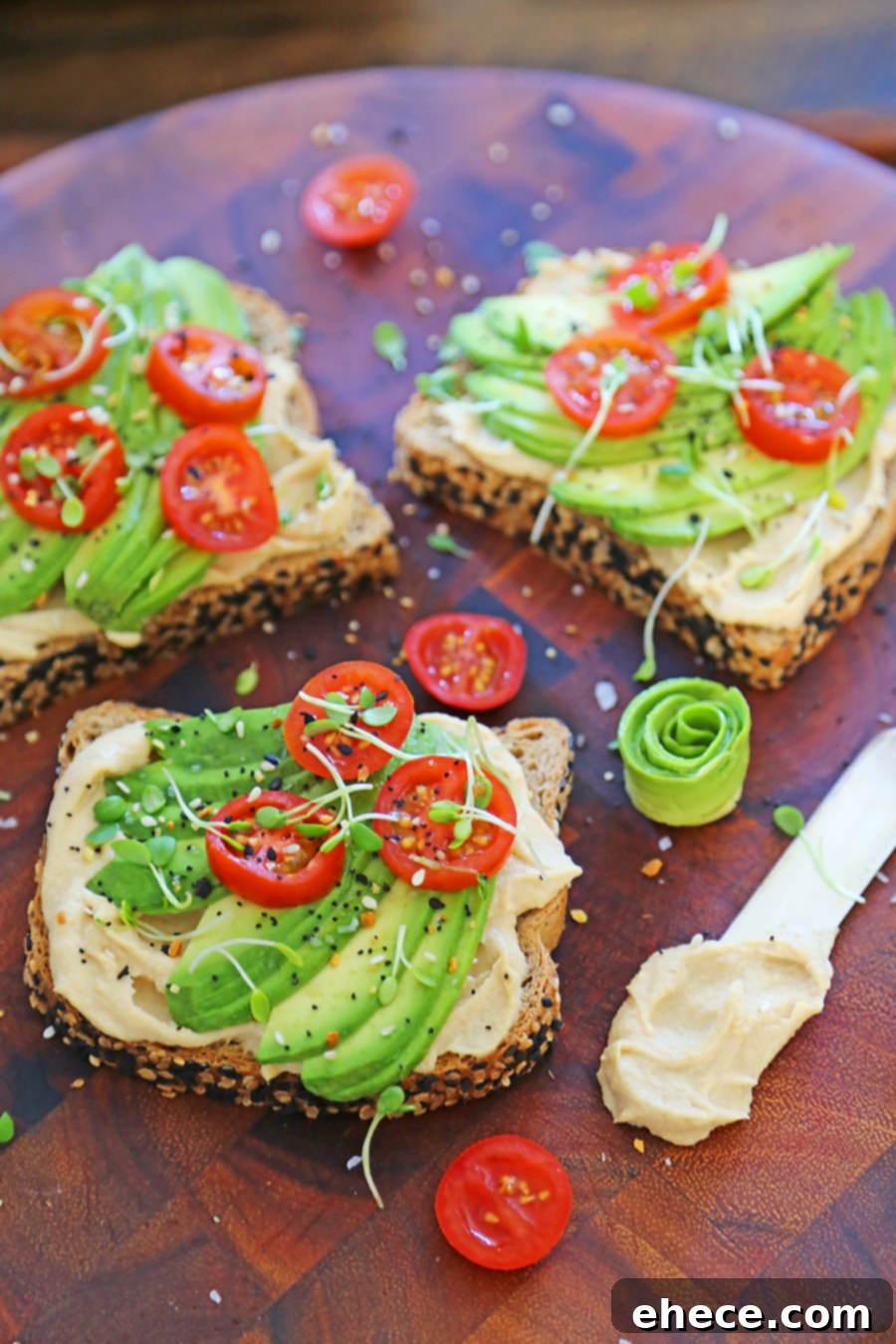 Quick Creamy Hummus Avocado Toast 4 Three slices of hummus avocado toast presented beautifully on a marble surface with fresh ingredients.