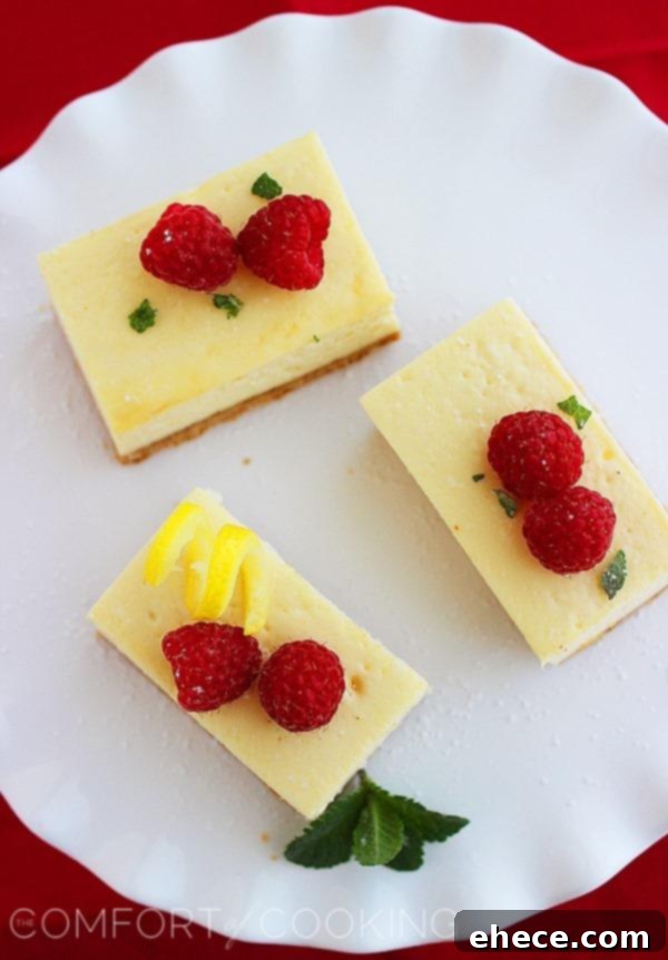 Tangy Lemon Cheesecake Bars 3 Close-up of a perfectly sliced lemon cheesecake bar, revealing its thick, creamy filling, crunchy graham cracker crust, and fresh berry topping.