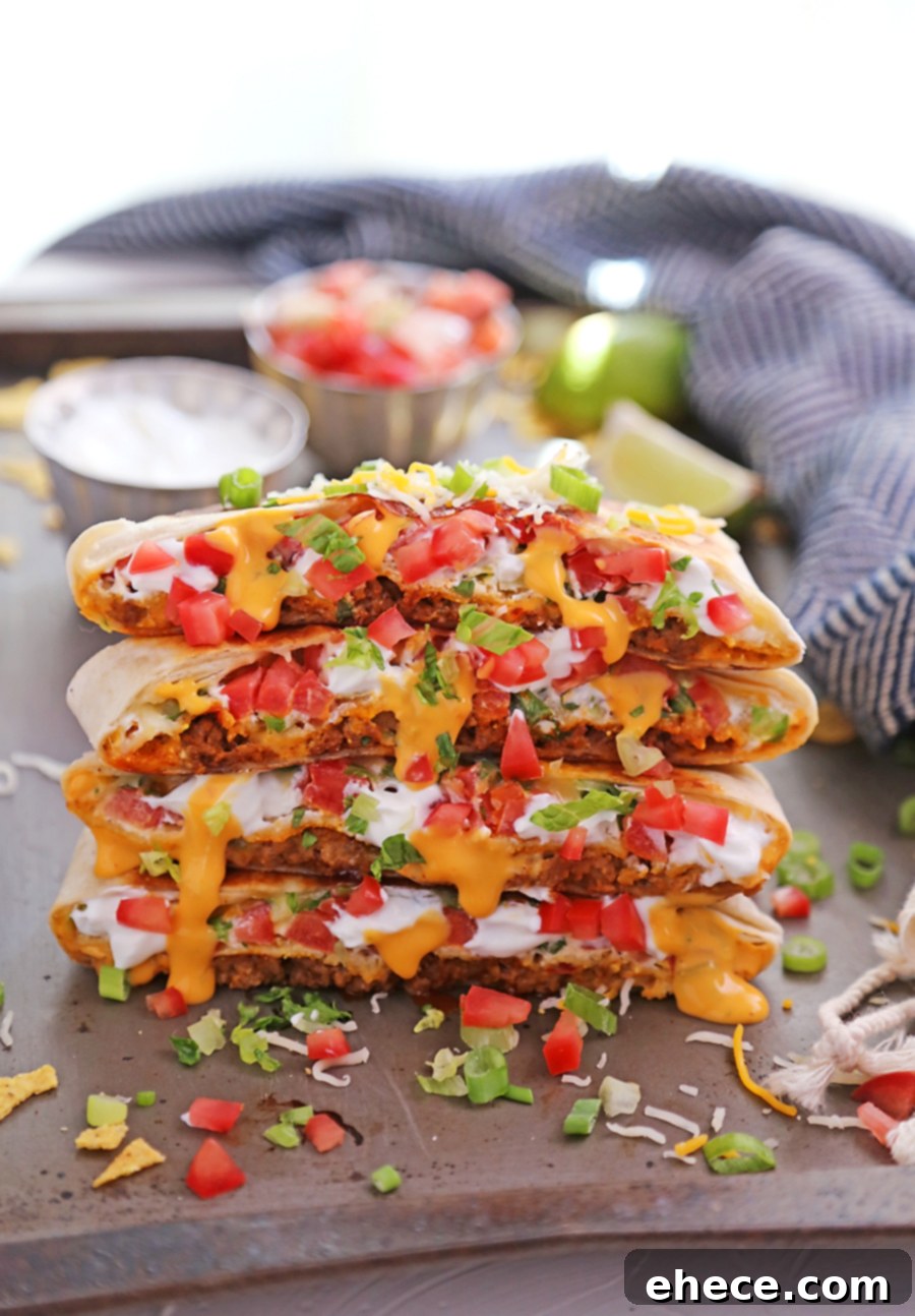 Two halves of a homemade Crunchwrap Supreme on a black surface, highlighting the melty cheese