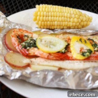 A vibrant foil packet of grilled New England seafood bake, showcasing flaky fish, plump shrimp, and sliced potatoes with fresh herbs and lemon.