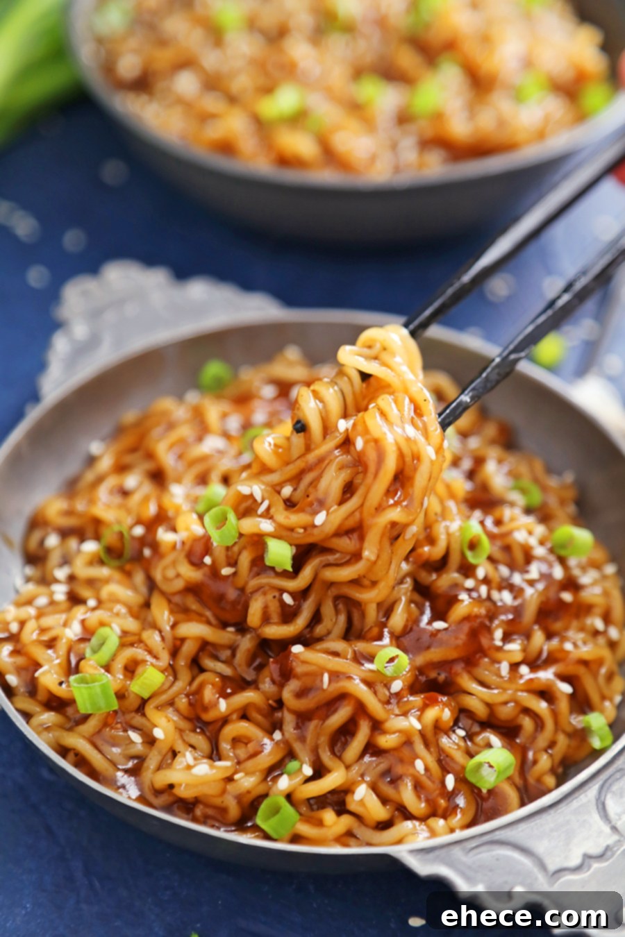 Overhead shot of a bowl of saucy ramen noodles, with chopsticks poised to pick up noodles.