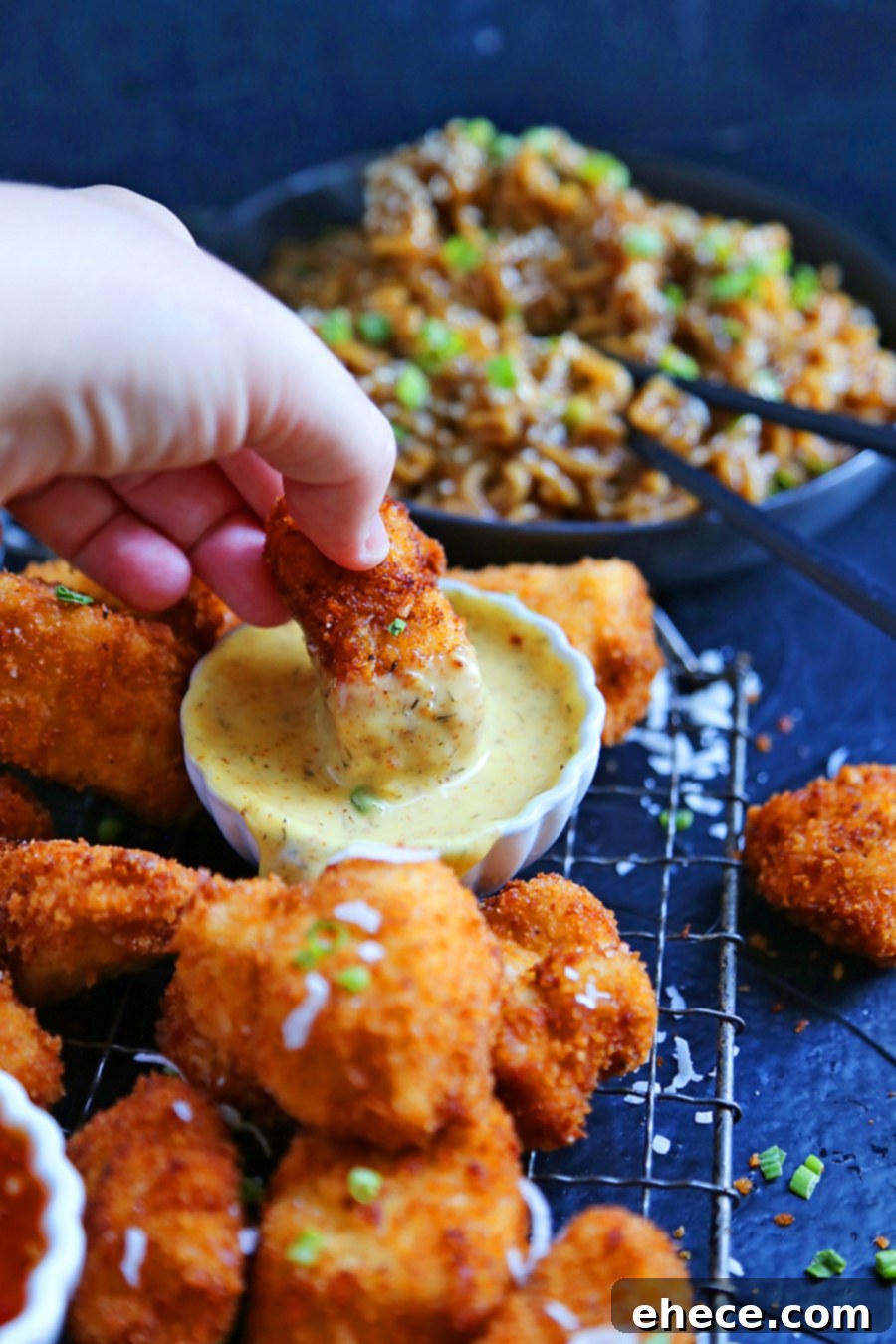 Tropical Crunch Popcorn Chicken 3 Close-up of golden brown crispy coconut popcorn chicken with a bowl of honey mustard sauce in the background