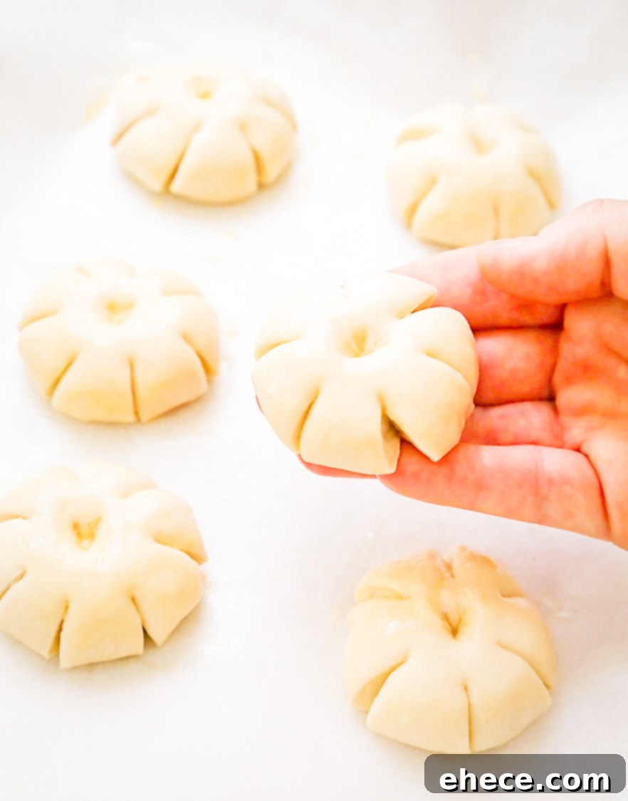Close-up of partially baked pumpkin dinner rolls, showing the scored lines.