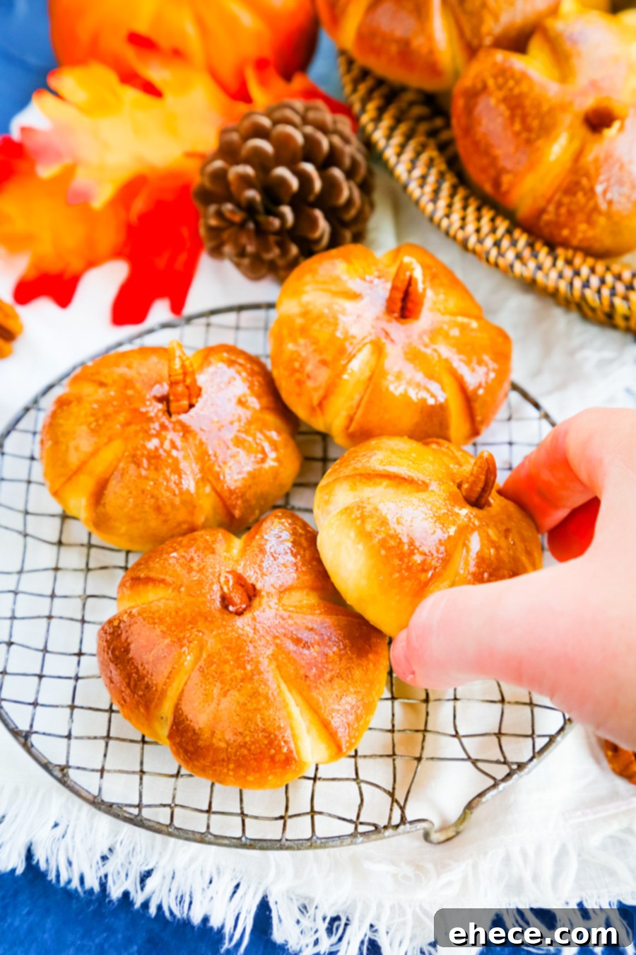 Freshly baked pumpkin dinner rolls brushed with butter and topped with pecan stems.