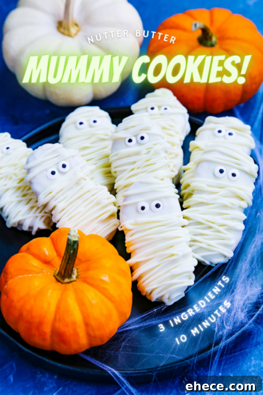 A close-up of several Nutter Butter Mummy Cookies on a white surface, showcasing their detailed white chocolate bandages and expressive candy eyes.