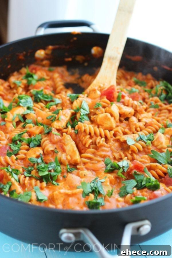 One-Pan Creamy Tuscan Chicken Pasta 4 A large skillet filled with Creamy Italian Chicken & Pasta, garnished with fresh herbs, ready to be served.