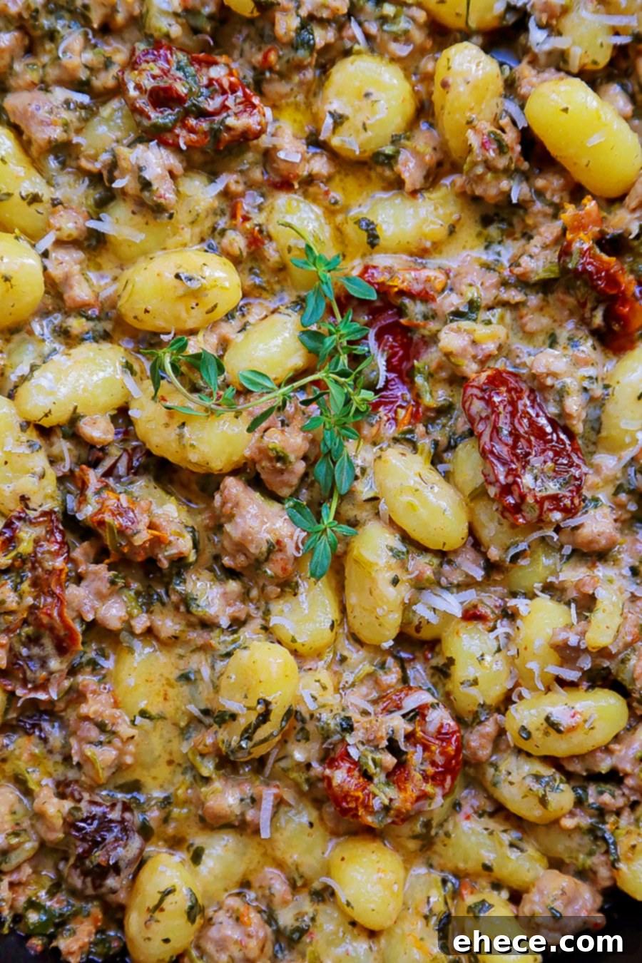 Close-up of a serving of Creamy Tuscan Sausage Gnocchi in a bowl, garnished with fresh herbs.