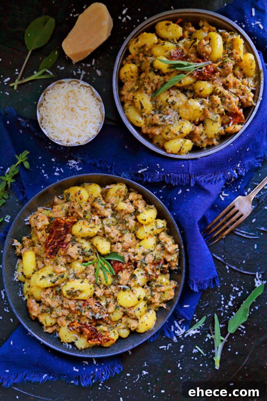 Serving of creamy gnocchi with sausage, sun-dried tomatoes, and spinach in a white bowl.