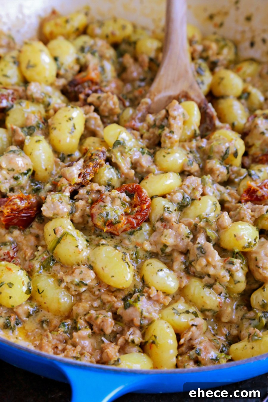 A bowl of Creamy Tuscan Sausage Gnocchi with a fork, ready to eat.