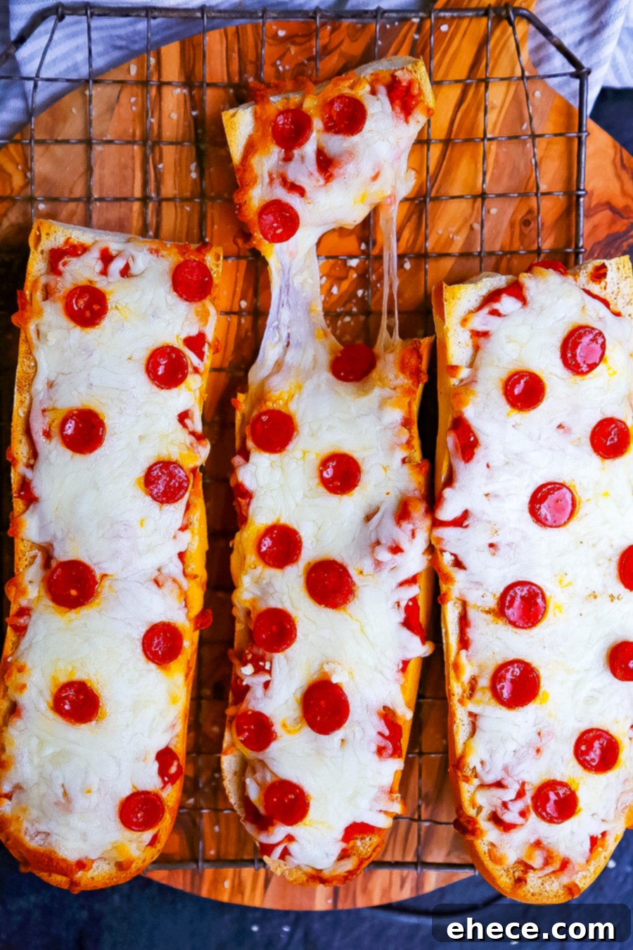 Close-up of French bread pizzas before baking, with sauce, cheese, and toppings