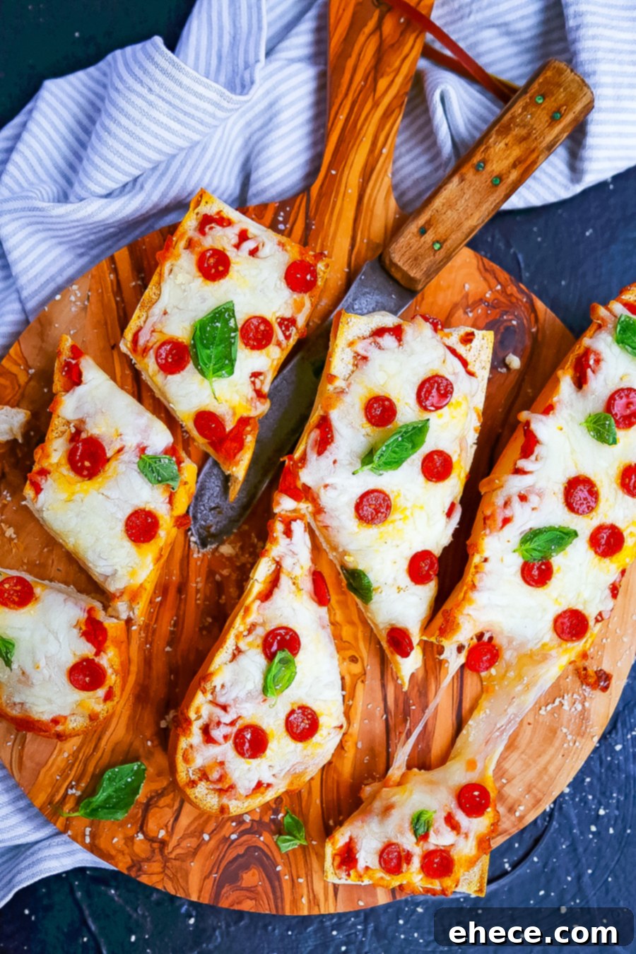 Three golden brown French bread pizzas fresh out of the oven, garnished with fresh basil