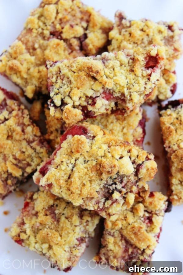Close-up of freshly baked Mixed Berry Crumble Bars, showing the juicy berry filling peeking through the crumbly topping.