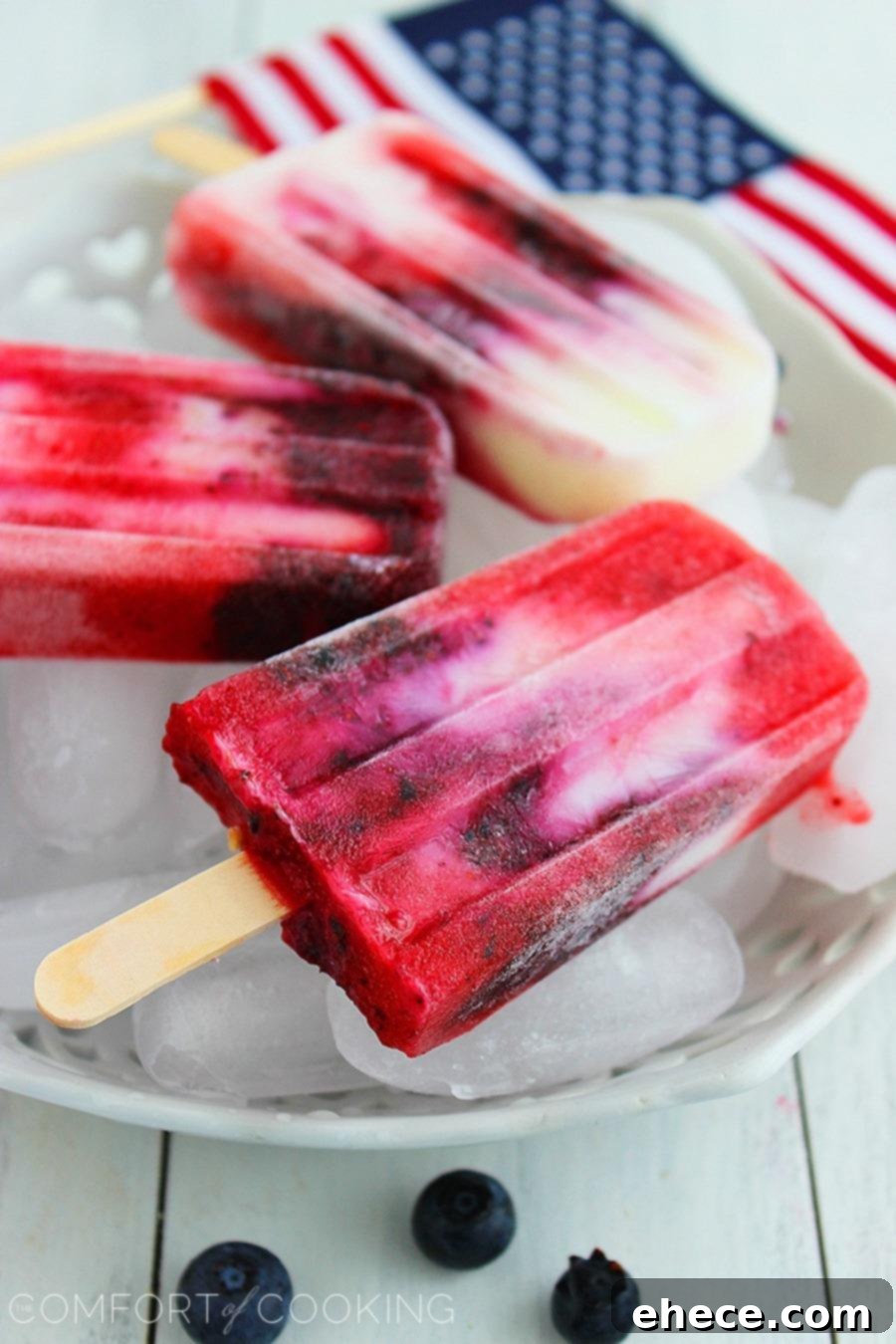 A tray of Firecracker Berry Frozen Yogurt Pops in molds, ready to be frozen, highlighting the distinct layers of fruit and yogurt.
